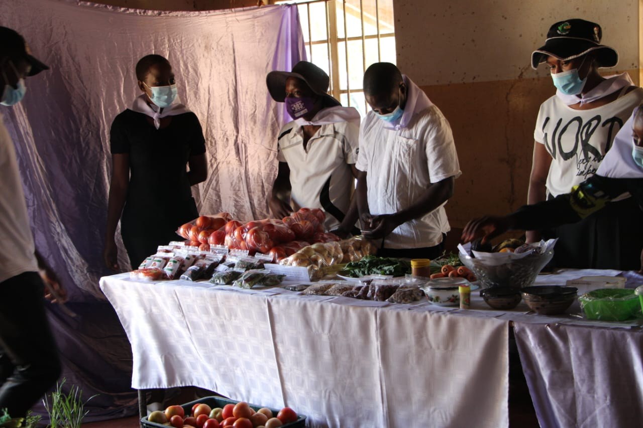 Youth and women displaying produce and training products